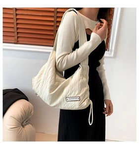 Detail of off-white pleated hobo bag with Superior woven label and drawstring side
