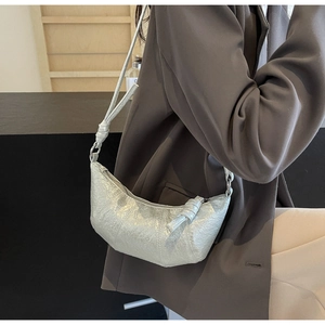 Detail shot of the silver metallic pleated croissant bag texture on a gray suit jacket