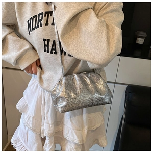 Close-up of a silver pleated cloud bag with metallic finish shown as a crossbody