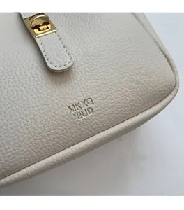 Dettaglio della pelle martellata avorio con chiusura a rotazione dorata della borsa