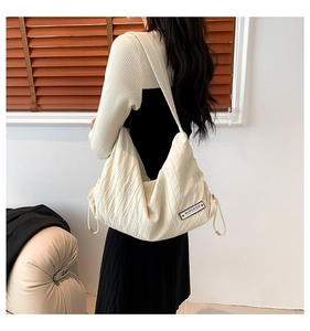 Detail of off-white pleated tote bag with light fabric texture and brown leather patch