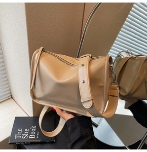 Détail du sac bandoulière beige montrant le cuir grainé et la bandoulière large