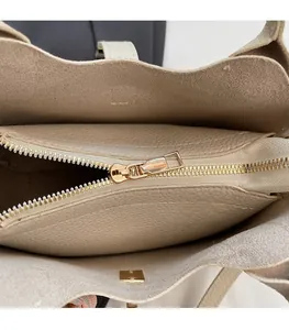 Dettaglio dell'interno della borsa a secchiello beige con cerniera in metallo dorato