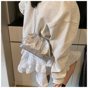 Silver metallic pleated cloud bag shown with a long shoulder strap on a fashion model