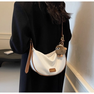 Detail of white leather crescent bag with brown trim and cute plush eye charm