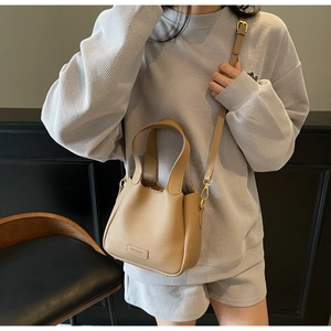 Close-up of khaki bucket bag with litchi leather texture and golden hardware details