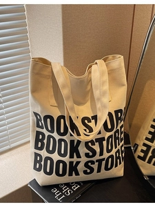 Sac fourre-tout minimaliste en toile beige avec imprimé Bookstore posé près d'une fenêtre