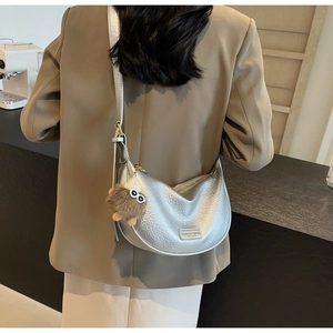 Silver metallic hobo bag with grainy texture and a cute brown plush monster charm