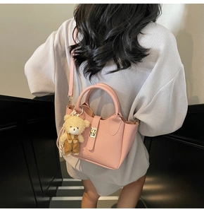 Dettaglio della borsa rosa motivo litchi con ciondolo a orsetto su una modella