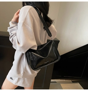 Détail du sac oreiller en cuir verni noir brillant avec bandoulière large et argent