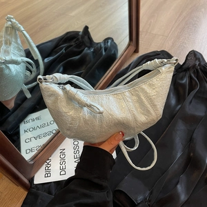 Detail of silver crescent croissant bag with wrinkled metallic texture and knotted handle