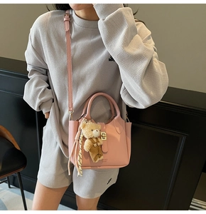 Borsa a secchiello rosa a grana litchi con ciondolo a orsetto e foulard a righe