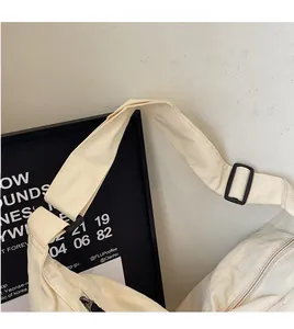 Detail view of beige canvas crossbody bag with adjustable wide strap and metal zipper