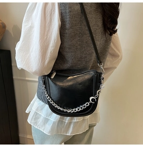 Detail of black PU leather saddle bag with silver chain and crescent moon charm accessory