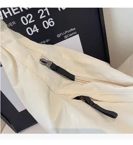 Detail of a beige canvas tote bag featuring a smooth black metal zipper and fabric puller