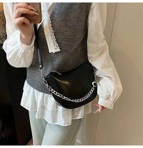 Detail of black leather saddle bag with silver chain and crescent moon charm on model