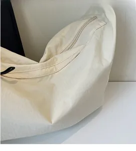 Close-up of the pleated nylon fabric and zipper closure on the off-white crescent bag