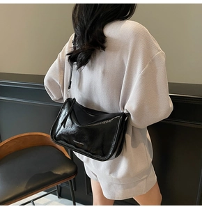 Détail du sac bandoulière en cuir verni noir brillant avec logo MAUDAI BEAR blanc