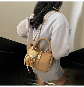 Borsa a secchiello in pelle kaki con ciondolo a forma di orsetto indossata da modella