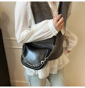 Detail of black semi-circle crossbody bag featuring chunky silver chain and moon charms