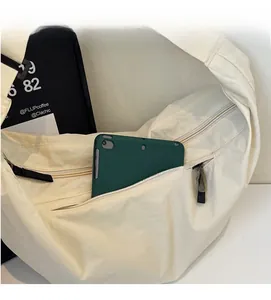 Detail view of large zipper pocket on nylon crossbody bag holding a green tablet