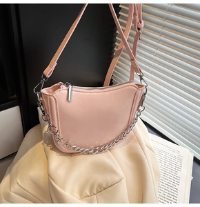 Top view of a pale pink semi-moon saddle bag with glossy texture and silver chain strap