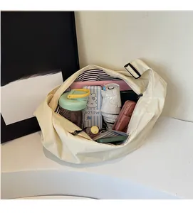 Spacious interior of beige crescent crossbody bag filled with daily essentials and tablet