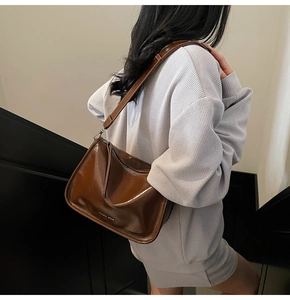 Détail du sac à bandoulière en cuir verni marron foncé avec bandoulière réglable