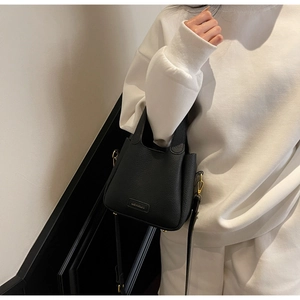 Close-up of black leather bucket bag with gold hardware and Chidlate brand plate