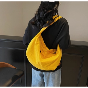 Detailed back view of a large bright yellow crescent shoulder bag on a female model