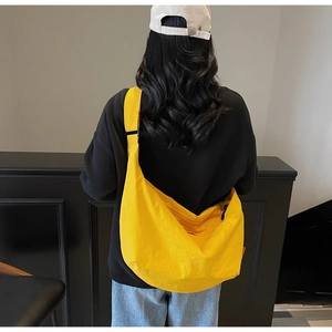 Detailed back view of a large yellow crescent canvas crossbody bag with wide strap