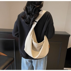 Detailed back view of a minimalist beige crescent tote bag with an orange side label