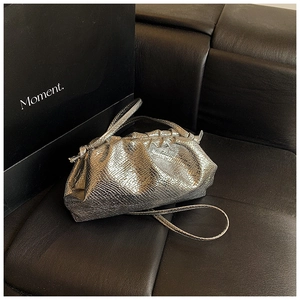 Detail shot of silver metallic pleated cloud bag with textured finish and slim strap