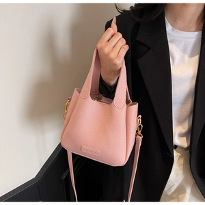 Detail shot of pink lychee textured leather bucket bag with gold hardware and logo
