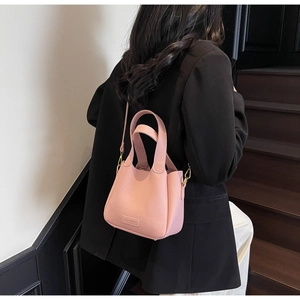 Detail showing pink lychee textured leather mini bucket bag with gold-tone hardware