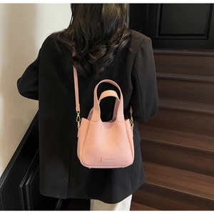 Pink lychee grain leather bucket bag with top handles and a detachable shoulder strap
