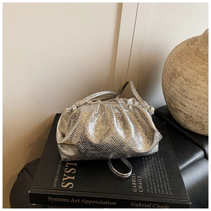 Detail of silver metallic pleated cloud bag with snake pattern texture on a book