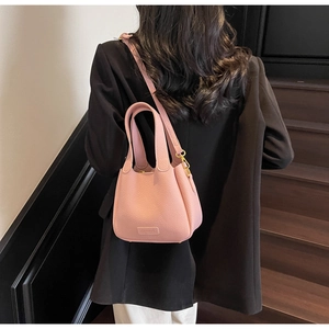 Detail of pink pebbled leather bucket bag with adjustable strap and metal hook