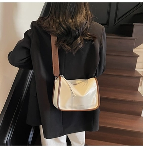 Détail du sac bandoulière crème et marron avec logo MAIDAI BEAR porté par mannequin