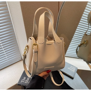 Close-up of cream pebble grain leather bucket bag featuring gold-tone hardware detail