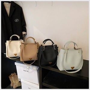 Litchi pattern bucket bags in four colors with gold handles on a wooden shelf