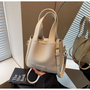 Detail of cream lychee texture leather bucket bag with gold hardware and dual handles