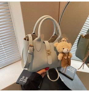 Dettaglio borsa azzurra in pelle martellata con chiusura dorata e ciondolo a forma di orsetto