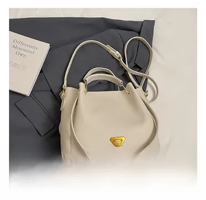 Detail view of cream lychee texture leather bucket bag with gold triangle logo hardware