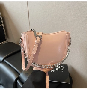 Close-up of light pink crescent saddle bag with silver chain and moon charm