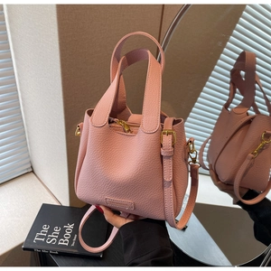Detail of pink lychee grain leather bucket bag with metal hardware and thin shoulder strap