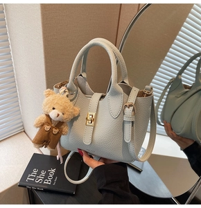 Dettaglio borsa in pelle azzurra con motivo litchi e ciondolo a forma di orsetto