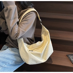 Detailed view of beige crescent tote bag with wide strap on a lifestyle background
