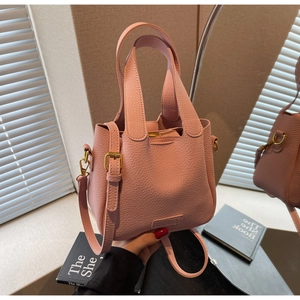 Detail of pink lychee leather bucket bag with gold hardware and removable shoulder strap