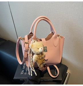 Dettaglio borsa rosa in pelle martellata con chiusura metallica e ciondolo a forma di orso